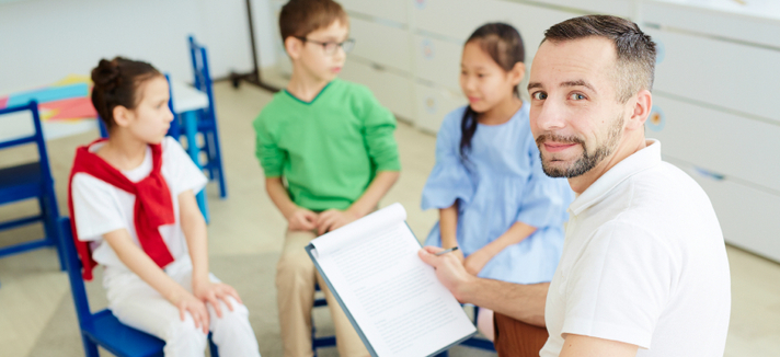 Ein Erzieher beschäftigt sich mit drei Kindern 
