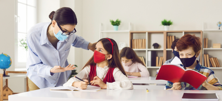 Lehrerin und Schülerin mit Maske zum Schutz im Unterricht